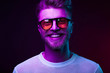 © monchak - Neon light portrait of smiling man model with mustaches and beard in orange sunglasses and white t-shirt