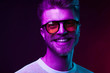 © monchak - Neon light portrait of smiling man model with mustaches and beard in orange sunglasses and white t-shirt