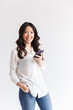 © Drobot Dean - Photo of positive asian woman with long dark hair holding and using black mobile phone, isolated over white background in studio