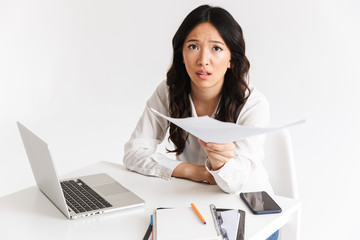 Poster - Photo of asian woman employee with long dark hair working in office with documents and laptop, isolated over white background