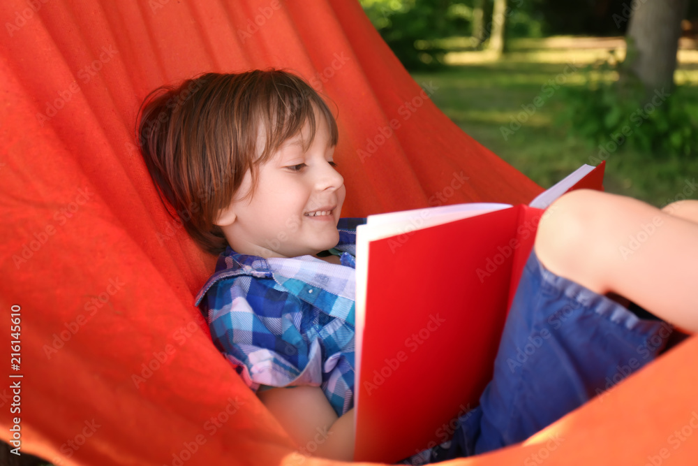 Cute little boy reading book in park