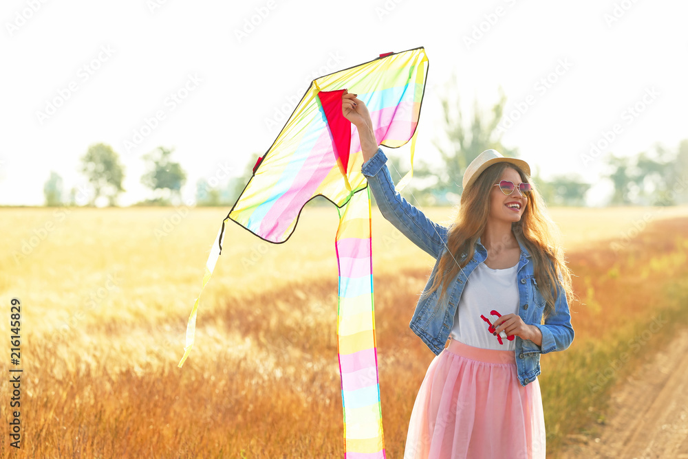 Beautiful young woman with kite in a field