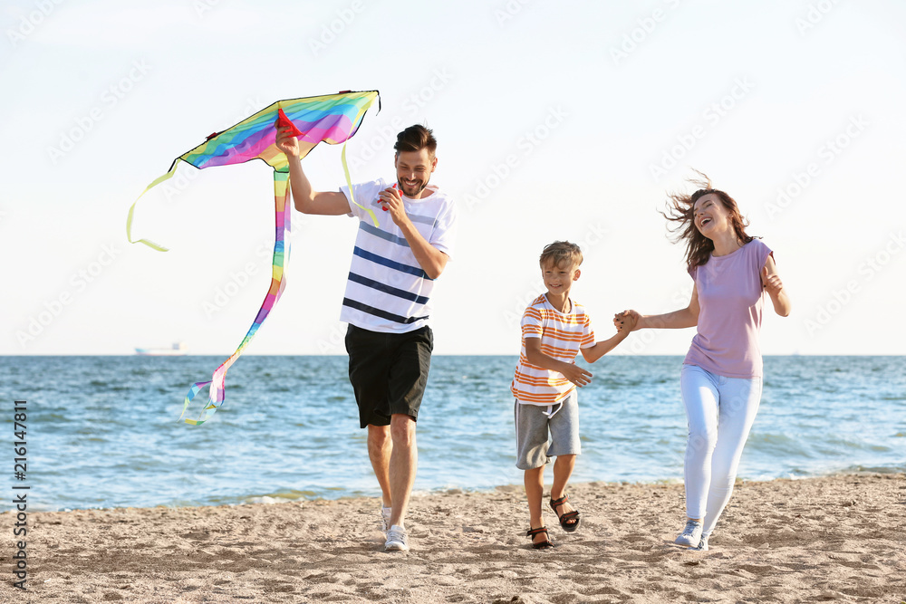 Happy family flying kite near sea