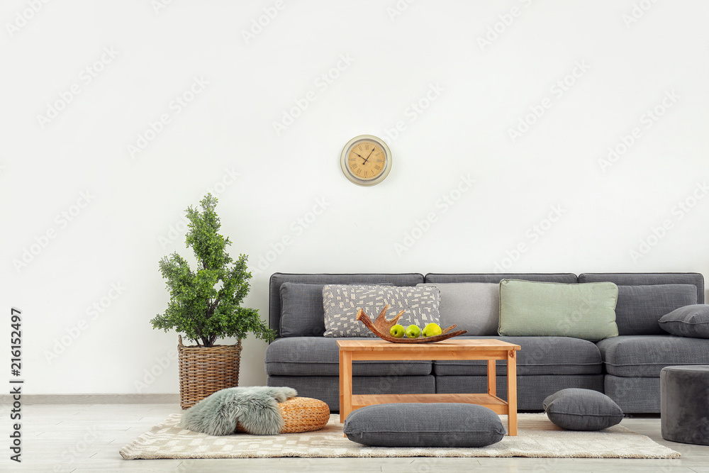 Stylish furniture with comfortable sofa near light wall