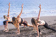 © simona - group of caucasian attractive girls woind exercises and pilates on the shore at the ocean. vacation and healthy lifestyle doing fitness outdoor in the nature. having fun in workout activity
