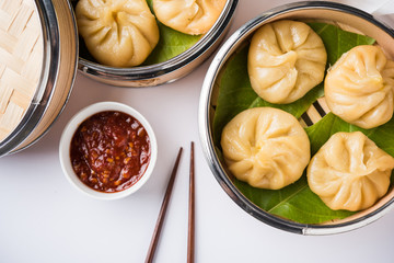 Traditional dumpling momos food from Nepal served with tomato chutney over moody background. Selective focus