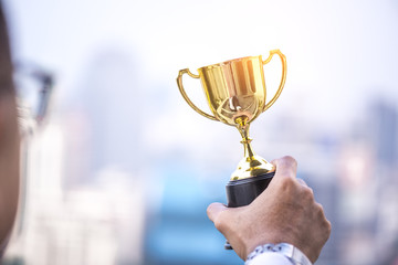 businessman hand holding gold trophy, business winner award