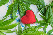 Love And Marijuana. Red Heart Against The Background Of Marijuana Leaves.