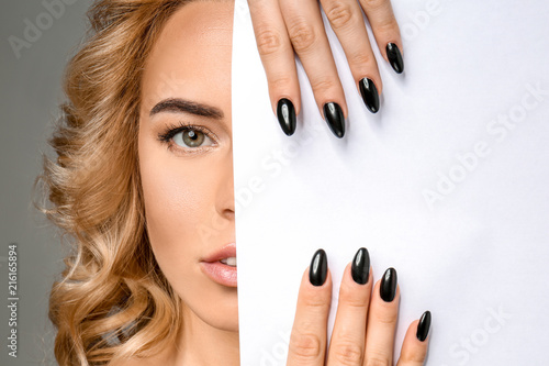 Plakaty do antyram, ramek lub samoprzylepne beautiful-young-woman-with-professional-manicure-and-blank-poster-on-grey-background