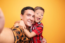 Little Boy And His Dad Taking Selfie On Color Background
