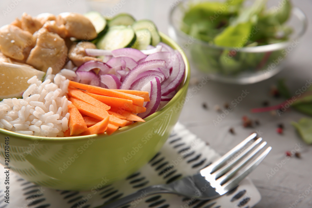 Bowl with tasty rice, vegetables and meat on table, closeup