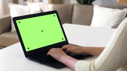 technology, virtual effects and programming concept - woman with chroma key green screen on laptop computer at home