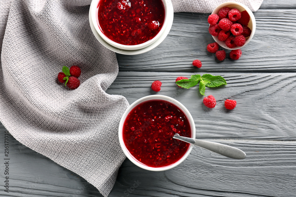Bowls with tasty raspberry jam on wooden table