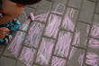 child draws colored pictures on chalk street, asphalt.