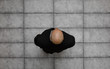 © serikbaib - bald businessman in black suit, top view, on gray concrete floor background.