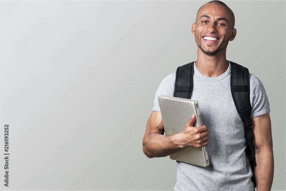 Portrait of smiling young african college student - obrazy, fototapety, plakaty 