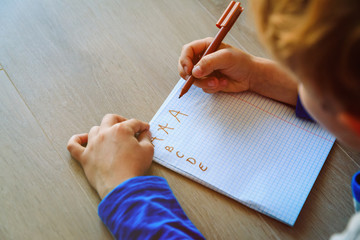 Wall Mural - little boy learning to write letters doing homework
