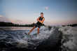 © fesenko - Young wakesurfer riding down the river waves crossing his hands at the sunset