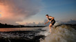 © fesenko - Athletic man riding on wakesurf down the river during sunset