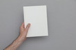 © ink drop - Male hand holding a closed book showing the book cover. Book Mock up template.