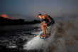 © fesenko - Young and active man riding on wakesurf down the river during summer sunset against the city