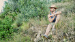 © starsstudio - Attractive, fit young man relaxing sitting in a grass field, wearing straw hat