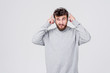 © oes - A young man with a beard in everyday clothes listens to pleasant music in wireless headphones. Gray background with space for text