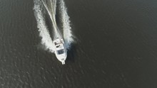 Luxury Speed Motor Boat Is Racing In The Sea At Sunny Day. Aerial View. Drone Is Flying Around Boat And Ascending, Camera Is Tilting Down. Spotlight Shot
