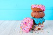 Stack of donuts with pastel colored icing on a soft blue background