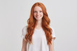© timtimphoto - Portrait of cheerful beautiful young woman with long wavy red hair and freckles looks happy and smiling isolated over white background