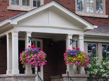 Covered Front Porch With Hanging Baskets Of Flowers