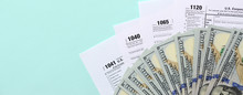 Tax Forms Lies Near Hundred Dollar Bills And Blue Pen On A Light Blue Background. Income Tax Return