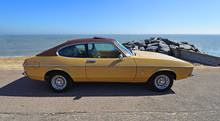 Classic Gold 2.0 Litre Ford Capri Ghia Motor Car Parked On Seafront Promenade.