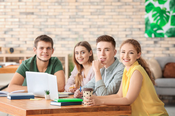 Wall Mural - Group of teenagers with laptops studying indoors