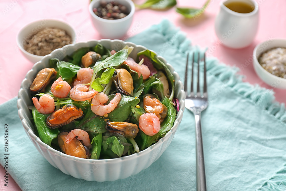 Bowl of delicious vegetable salad with seafood on table
