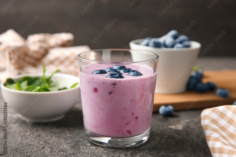 Glass of tasty blueberry smoothie on table