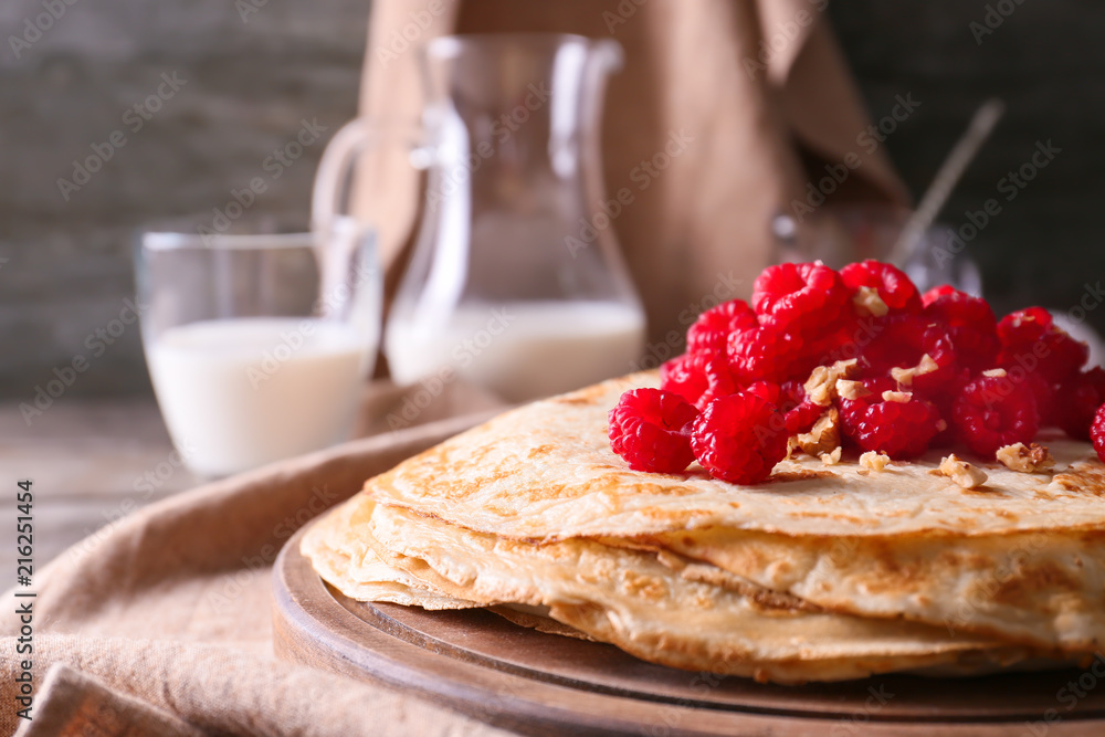 Delicious thin pancakes with berries and nuts on wooden board, closeup