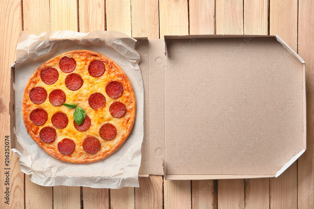 Tasty Pepperoni pizza in cardboard box on wooden table