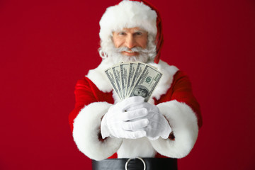 Santa Claus with dollar banknotes on color background