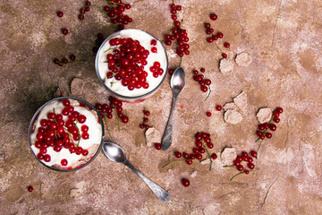 Wall Mural - Healthy dessert with organic red currants, fresh yogurt and corn flakes. Dietary breakfast on a brown background