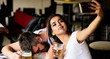 Take selfie to remember great event. Woman making fun of drunk friend. Man drunk fall asleep table and girl with full beer glass. Girl taking selfie photo drunk boyfriend. He appears too weak for her