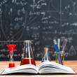 School supplies. Tubes with chemical liquids stand on a wooden table on a chalkboard background