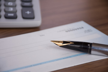 Wall Mural - Mock up image of cheque book, pen and calculator on wooden background.