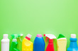 Colorful, chemical bottles for different surfaces cleaning in kitchen, bathroom and other rooms. Empty place for text or logo on green background. Cleaning service concept. Spring regular clean up.
