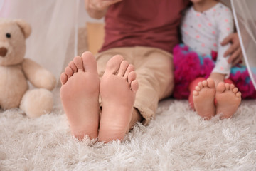 barefoot father and his little daughter sitting on carpet at home