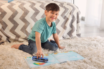 Wall Mural - Cute little boy playing and reading book at home