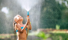 Cute Little Girl Pours Herself From The Hose, Makes A Rain. Hot Summer Day Pleasure