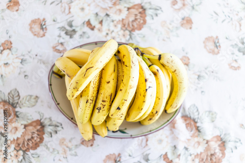 Fotografie, Obraz Closeup flat top view down of pile of many ripe spotted spotty yellow bananas on