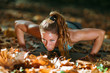 © Microgen - Woman doing push ups in the park, in the fall.