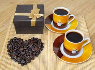 Two cups of coffee, a box with a gift and a heart made from coffee beans.